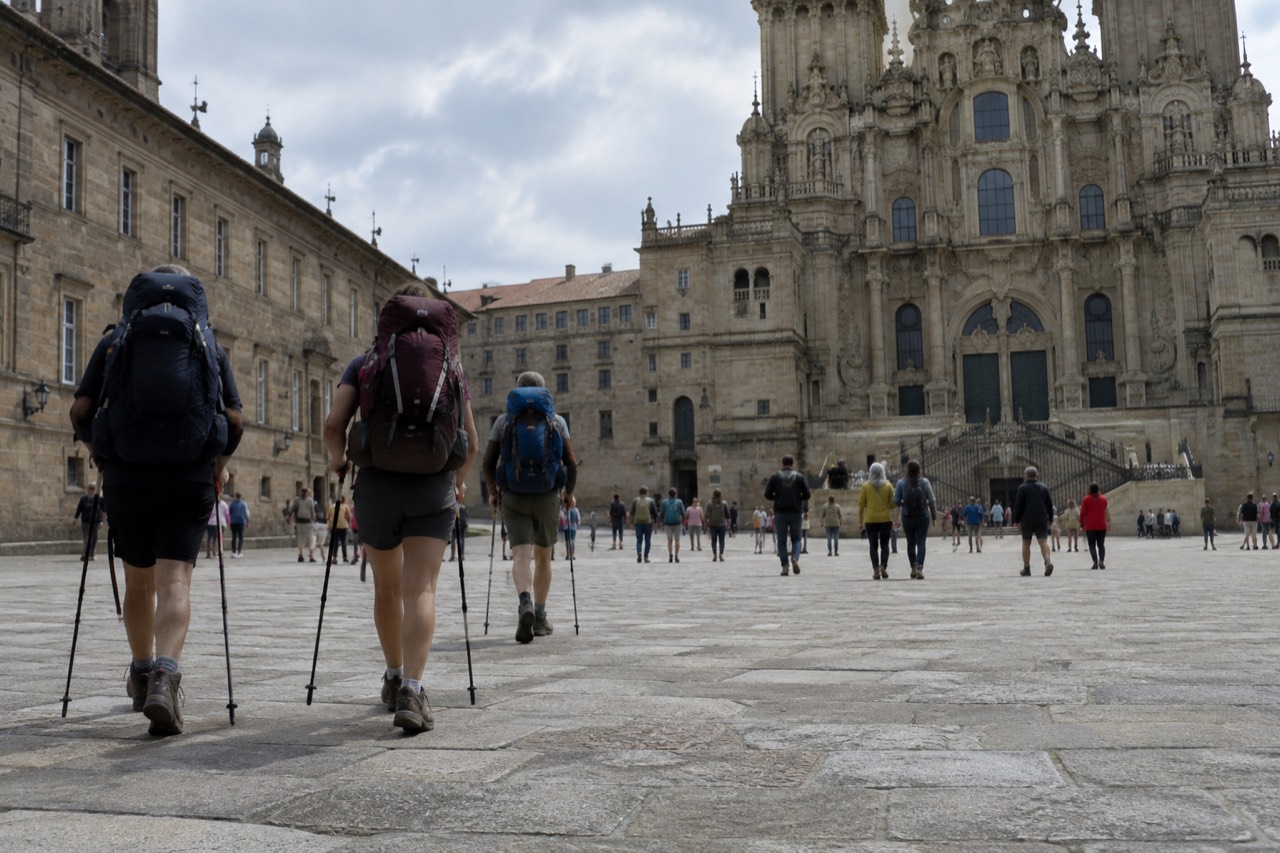Pilgrims with backpacks walking a cobbled street lane in northern Portugal on their way toward Santiago de Compostela