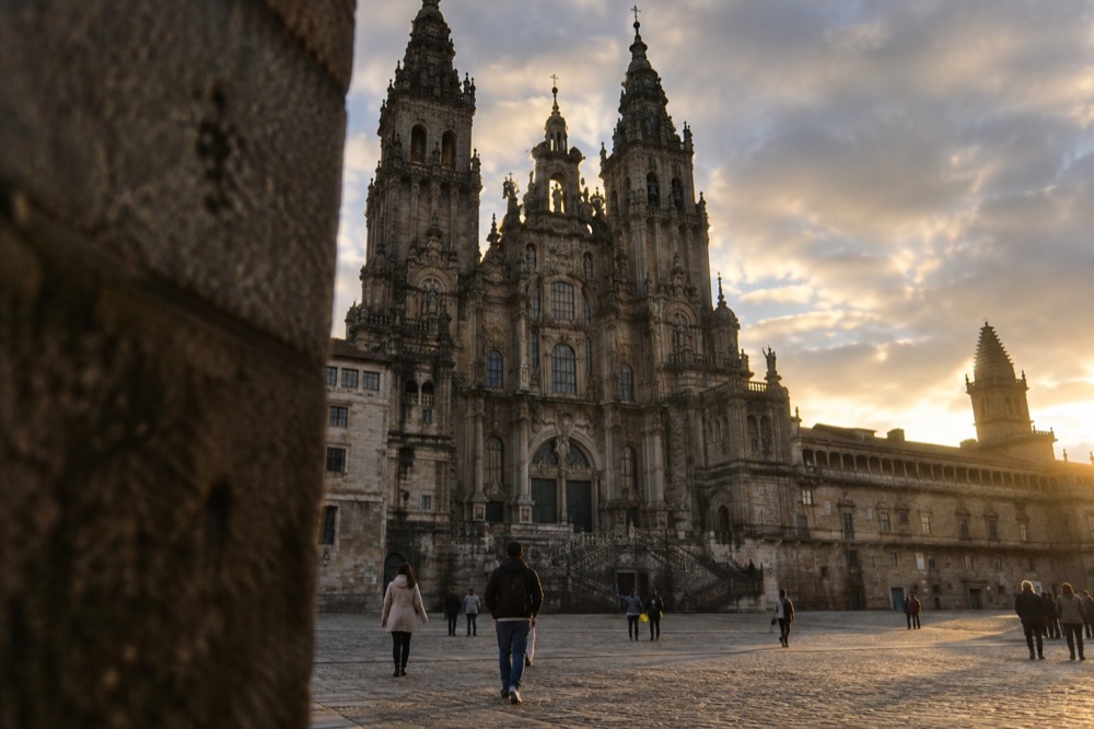 A bilingual street sign in Galician on a granite wall in Santiago de Compostela