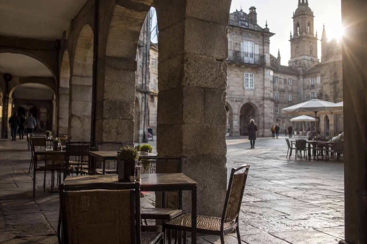 Granite arcade and cafe tables on a stone square in the old town of Santiago de Compostela