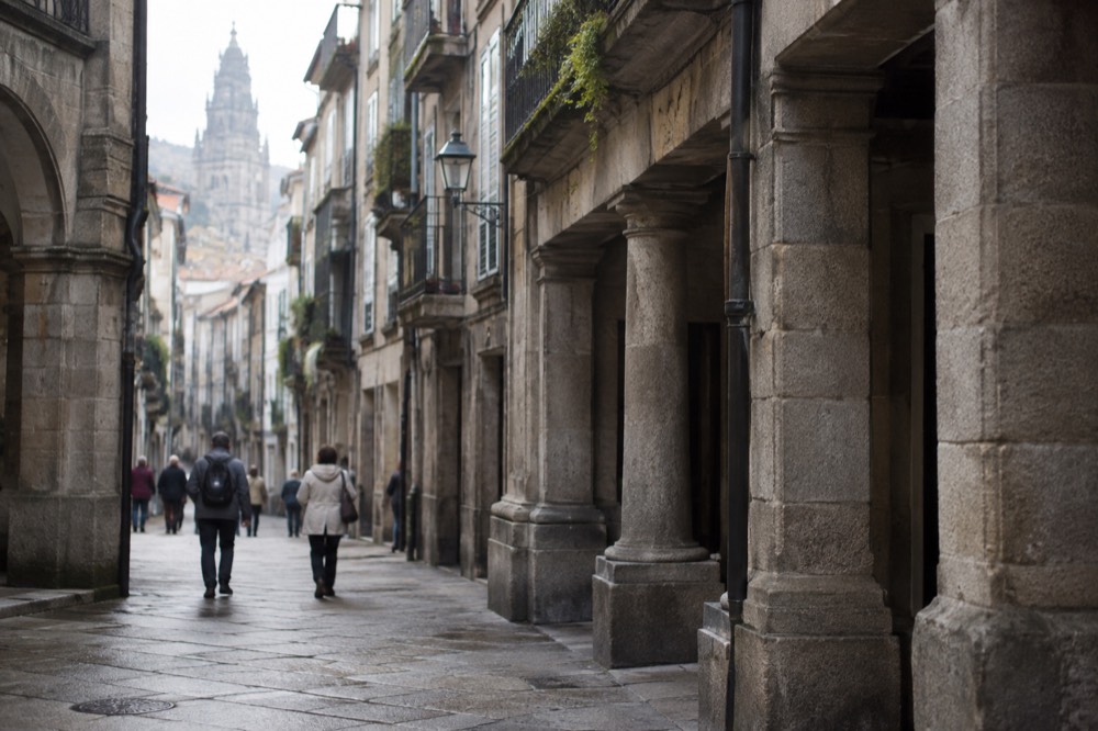 Granite streets and a stone archway in the old town of Santiago de Compostela on a soft morning