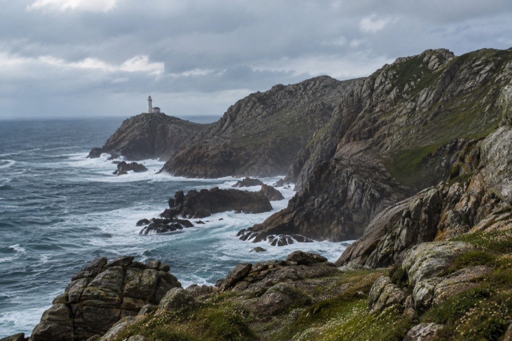 Coastal cliffs and a lighthouse on the Costa da Morte in Galicia, Spain, with the Atlantic Ocean beyond