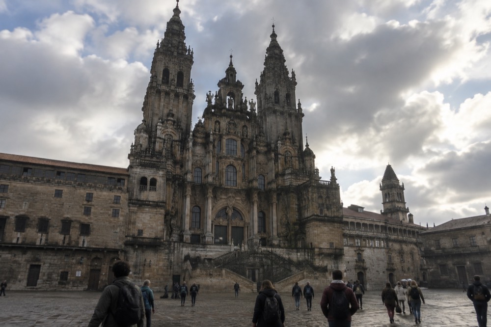 A train pulling into the modern station at Santiago de Compostela with travellers waiting on the platform