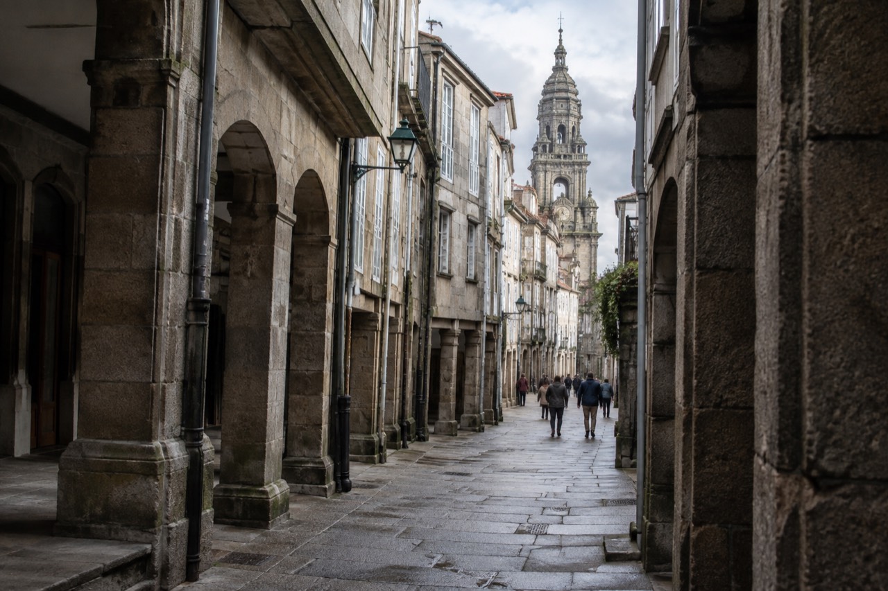 Granite buildings and a church tower in the old town of Santiago de Compostela under a soft sky