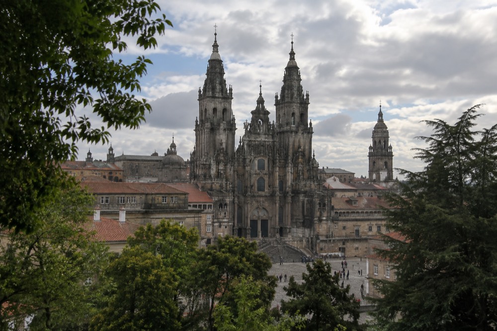 Cathedral towers and Baroque facade seen across treetops from the Paseo da Ferradura viewpoint in Alameda Park