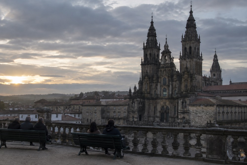 Evening light on the cathedral towers seen from the Ferradura balustrade, with people seated on park benches