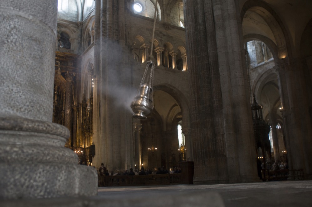 A large metal censer on ropes high above the stone floor of a Gothic cathedral transept