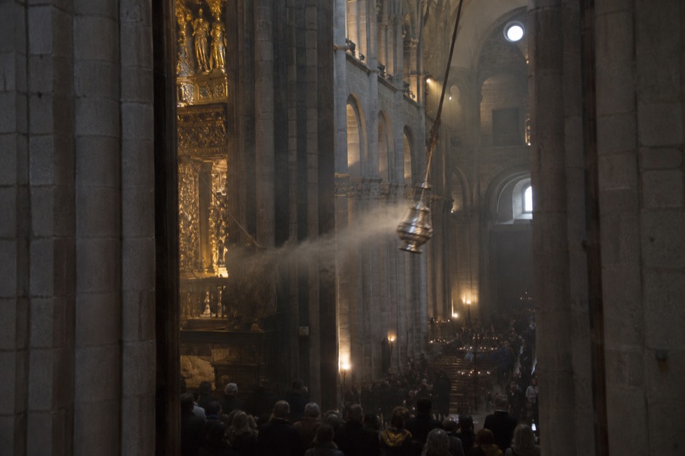 Crowds of pilgrims standing in a cathedral nave looking up toward the crossing tower