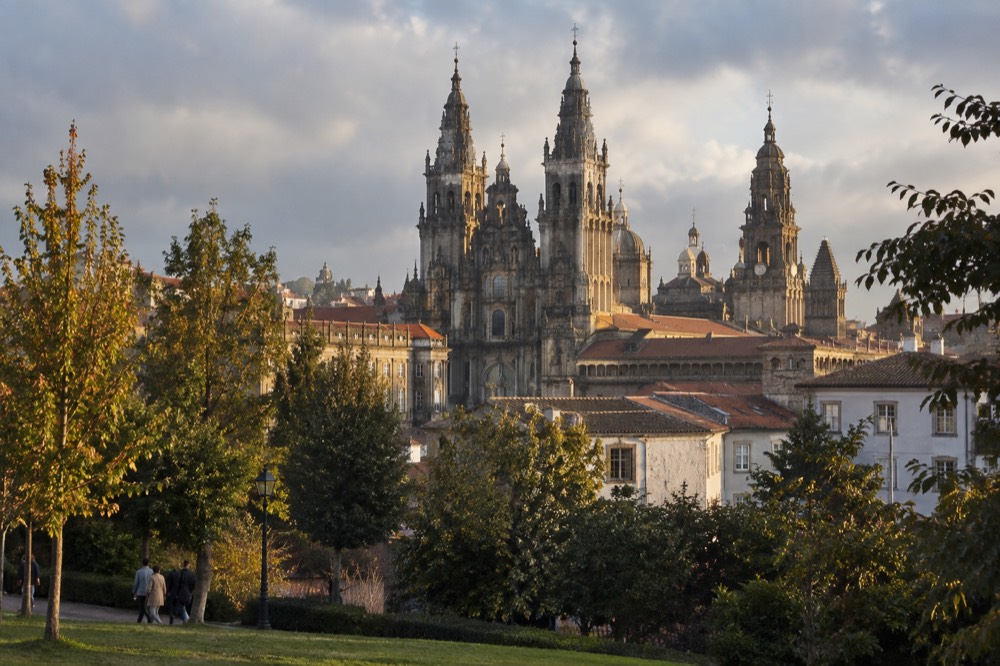 The cathedral skyline of Santiago de Compostela seen from a green park at golden hour