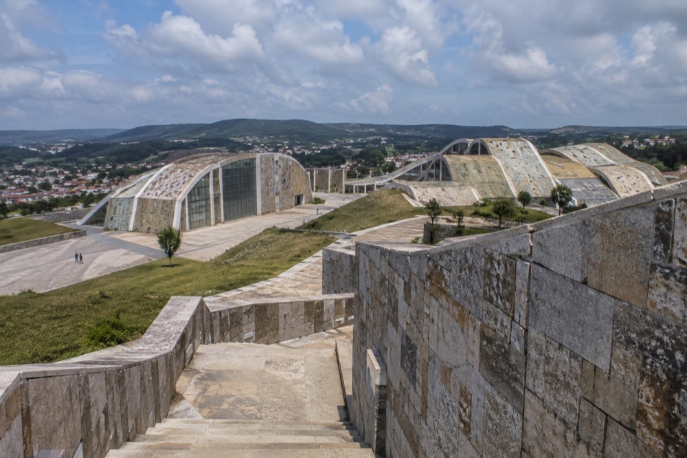 Interlocking pale stone walls and stairways of a modern cultural complex under a blue sky