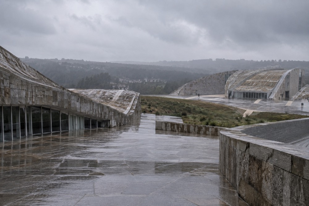 Wet stone terraces of a modern cultural complex under grey Galician rain clouds