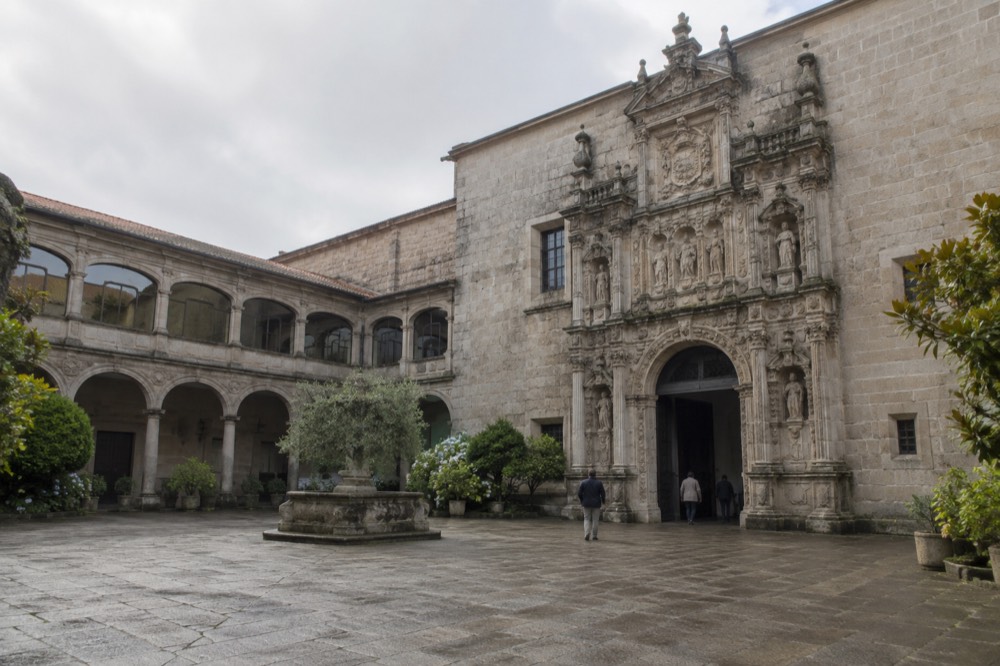 A stone arcade courtyard with plants and arched galleries inside the Parador building