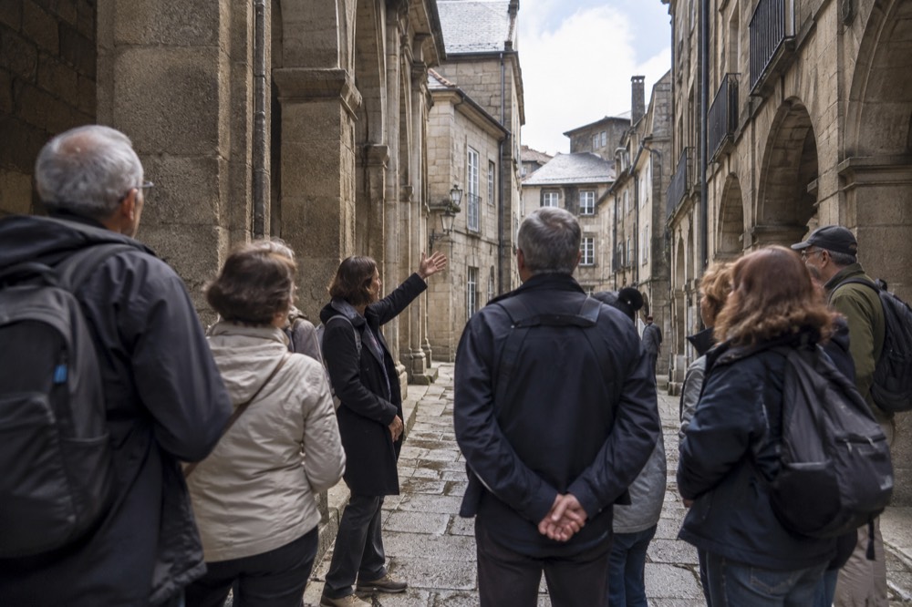 A guided group listening to a guide in a narrow granite street of the old town