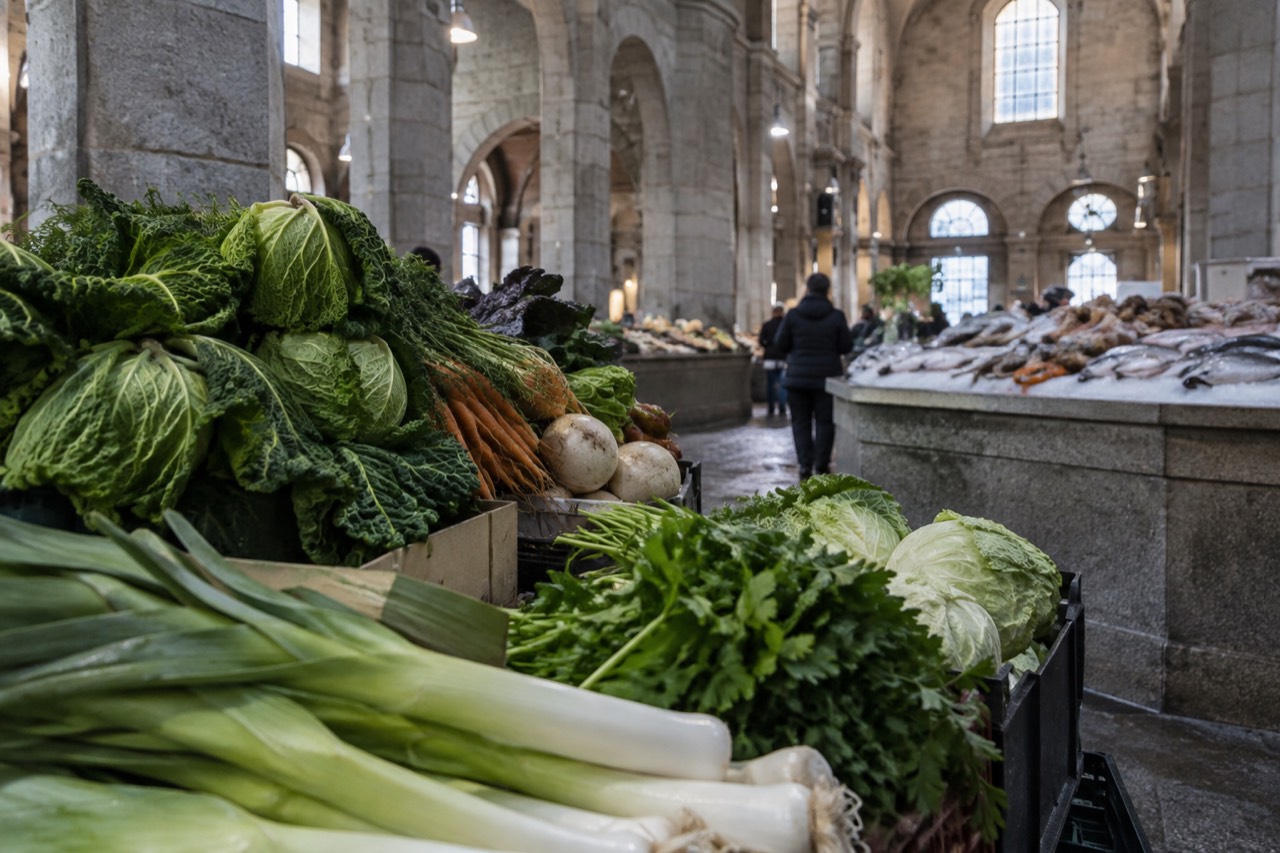 Fresh produce stalls under the stone arches of a Galician market hall