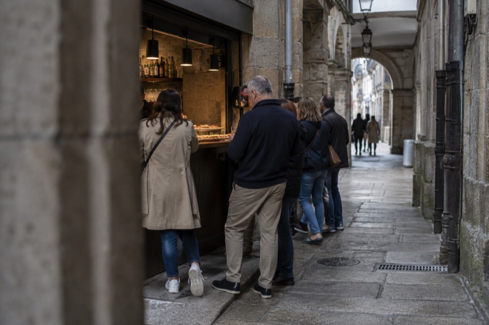 A guided food tour group sampling tapas at a small bar counter in the old town