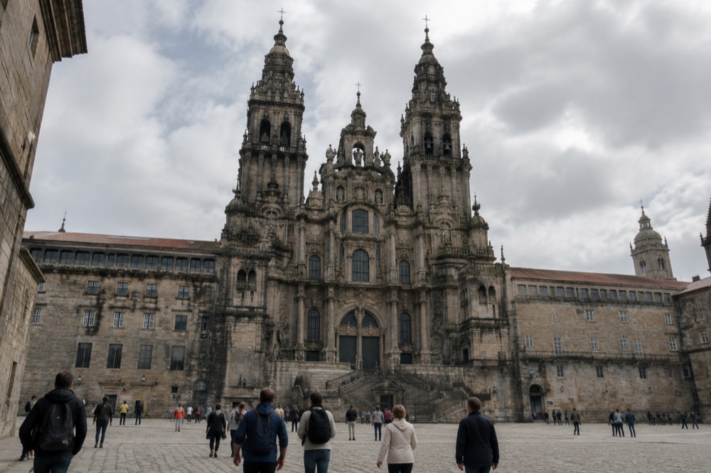Visitors walking through a museum corridor with stone walls and exhibit panels in Santiago de Compostela