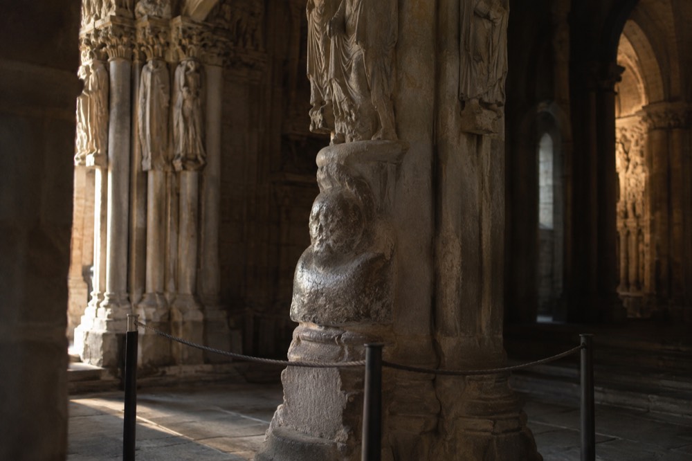 The central column and carved base of the Portico da Gloria with the worn stone head touched by pilgrims