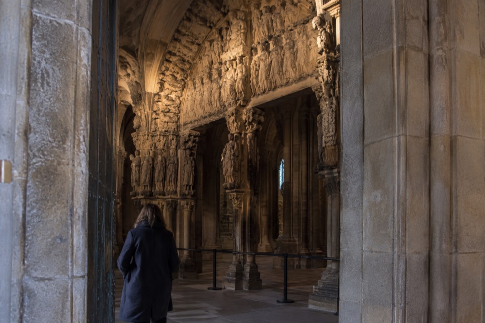 Sunlight falling across the carved elders and angels in the upper register of the Portico da Gloria