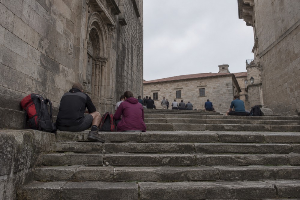 Pilgrims resting on the wide stone steps of Praza da Quintana in the late afternoon