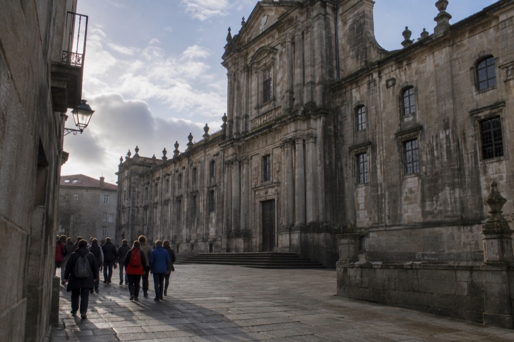 Walking tour group gathered in a granite lane of the old town near the San Martino Pinario monastery in Santiago de Compostela