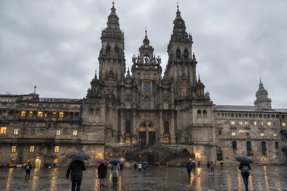 Rain-wet granite pavement reflecting the lights of the monastery facade in the evening in Santiago de Compostela