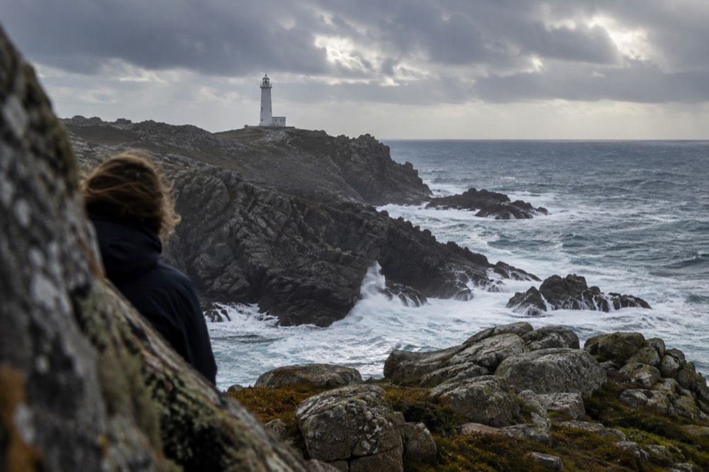 Lighthouse on a rocky cape above the Atlantic on the Costa da Morte coast with crashing surf below