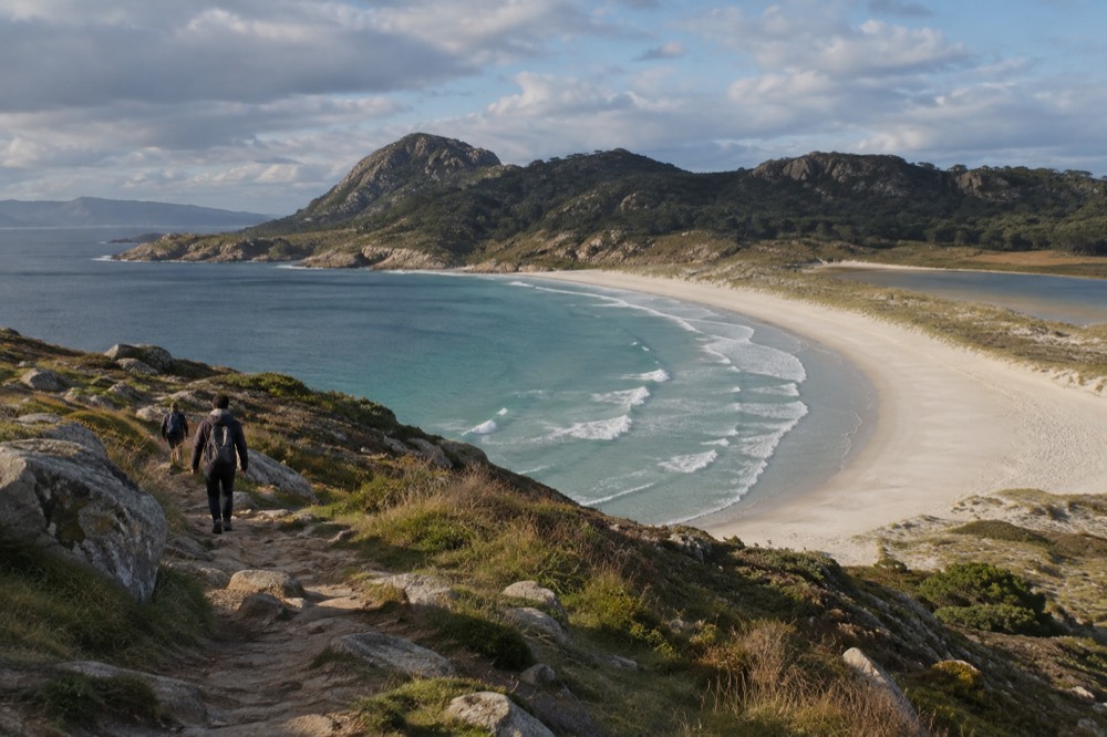 Walking path along a grassy island ridge with the sea on both sides