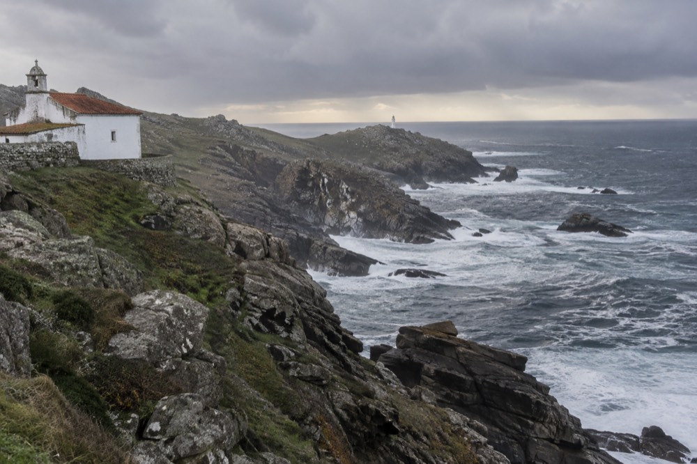 A whitewashed sanctuary church standing above a rocky Atlantic shoreline