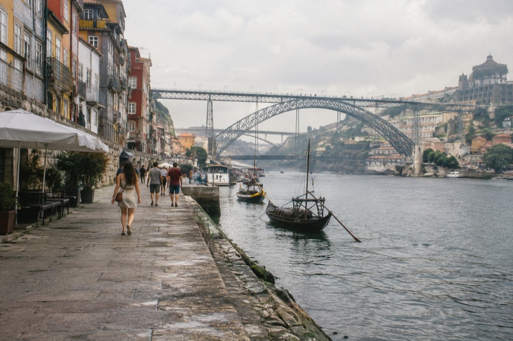 Colourful tiled facades stacked above a wide river in a historic southern European city