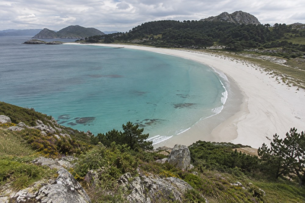 White sand beach and turquoise lagoon on the Cies Islands seen from a hillside path