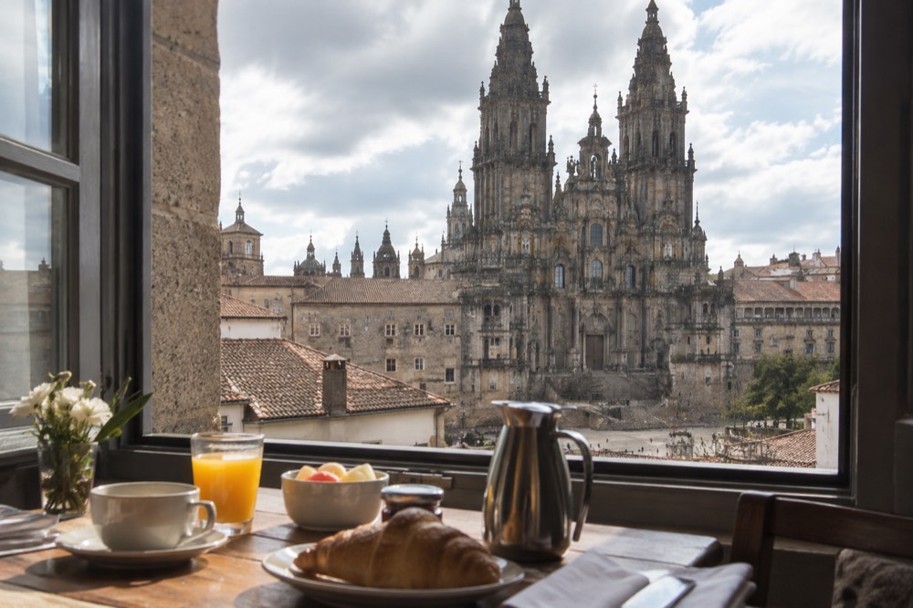 Breakfast table set beside a window with a view over the rooftops and towers of Santiago de Compostela