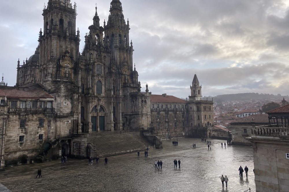 Regional train arriving at a modern station platform with the Santiago de Compostela skyline beyond