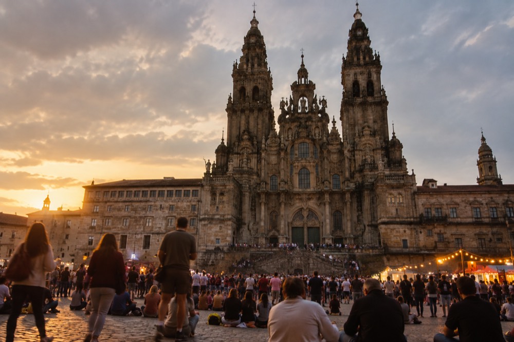 Festive lighting and crowds in a granite square during an evening celebration in Santiago de Compostela