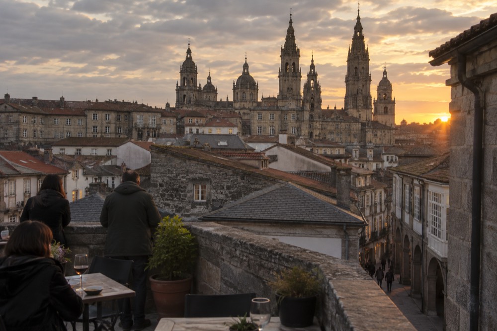 Visitors on a rooftop terrace looking out over the towers and rooftops of Santiago de Compostela old town