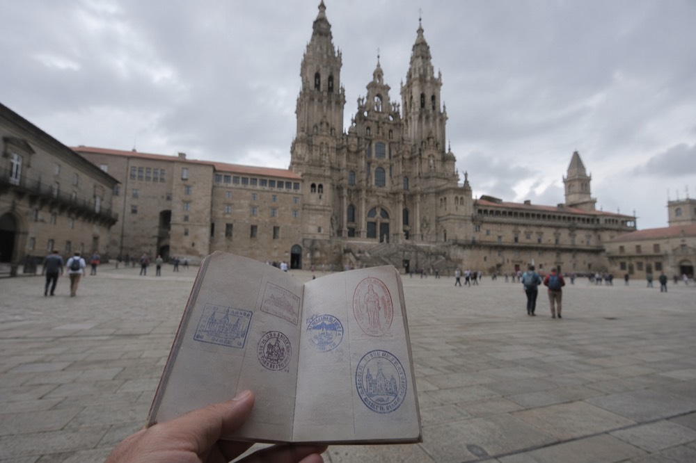 A credencial pilgrim passport held open showing ink stamps on its pages