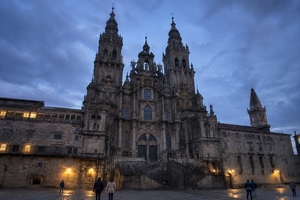 A stone square in the old town of Santiago de Compostela with the cathedral towers above the rooftops