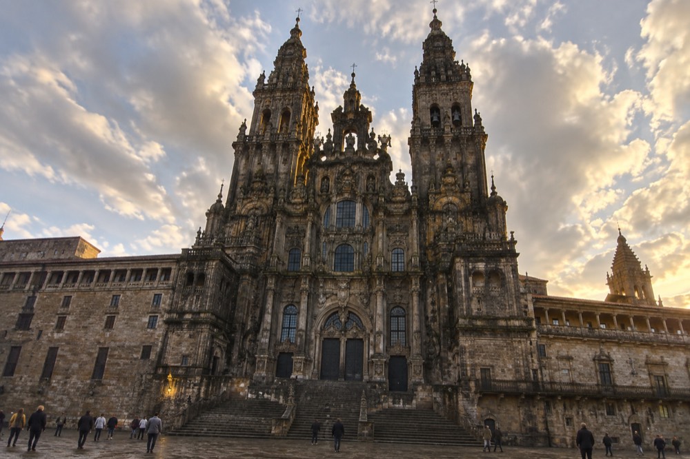 The baroque facade and twin towers of Santiago de Compostela cathedral seen from a large granite square