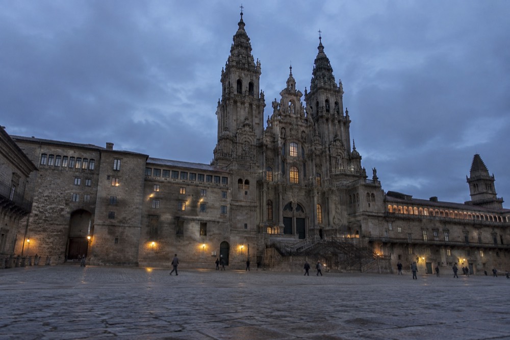 A pilgrim's walking boots, rain jacket and folded map laid out on a stone floor before a Camino departure