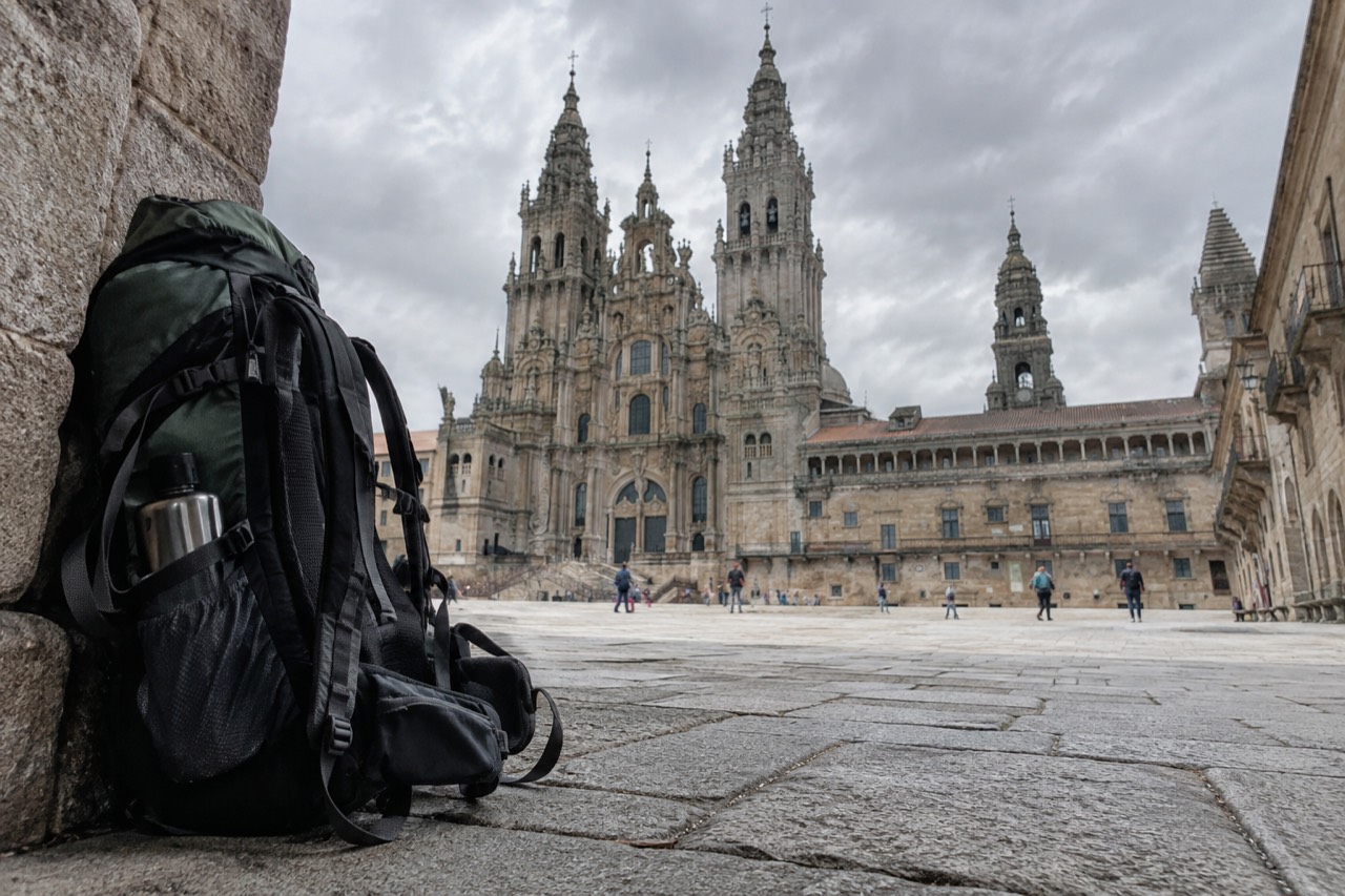 A pilgrim's backpack resting against a stone wall on a Camino path in Galicia
