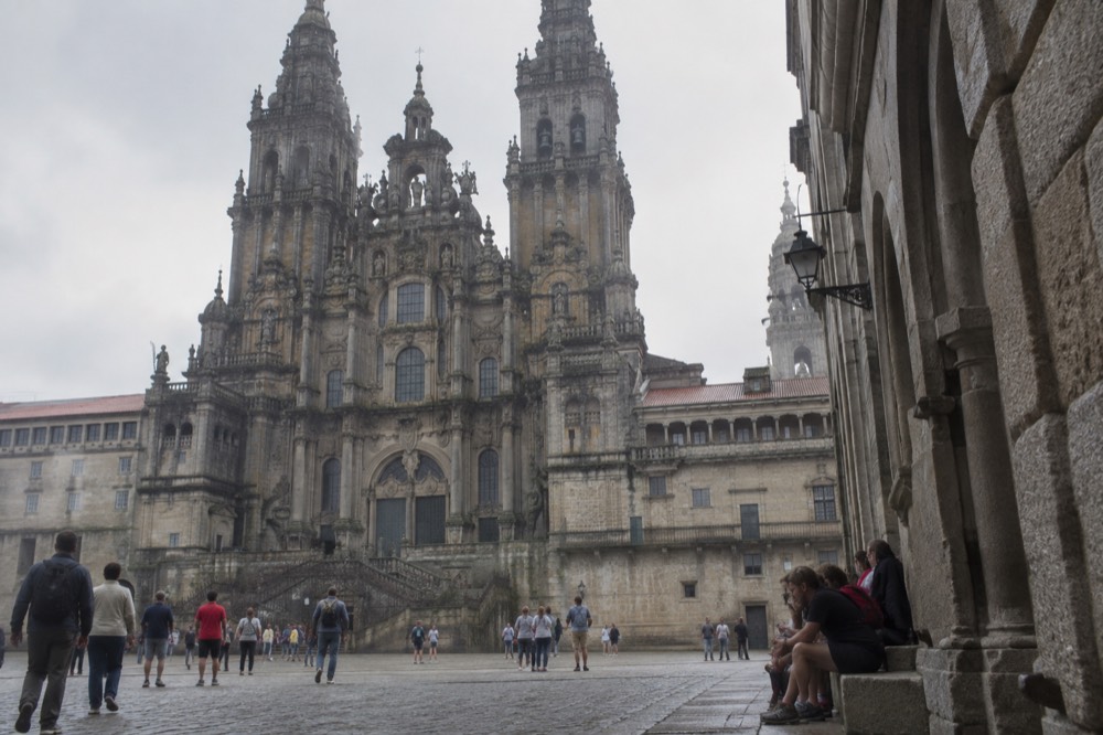 Walkers resting on a granite step in a narrow stone arcade street in Santiago de Compostela