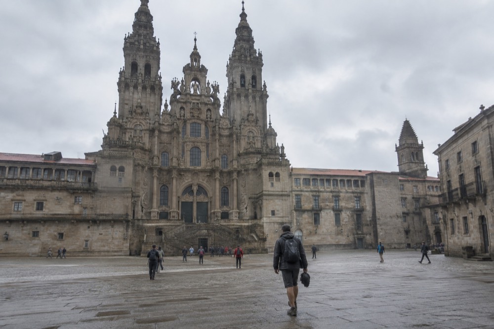 Walking boots, a rain jacket and a folded map laid out on a wooden hostel floor