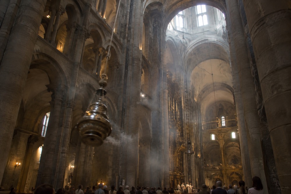 Pilgrims celebrating at the botafumeiro-less altar area of Santiago de Compostela Cathedral during a busy summer mass