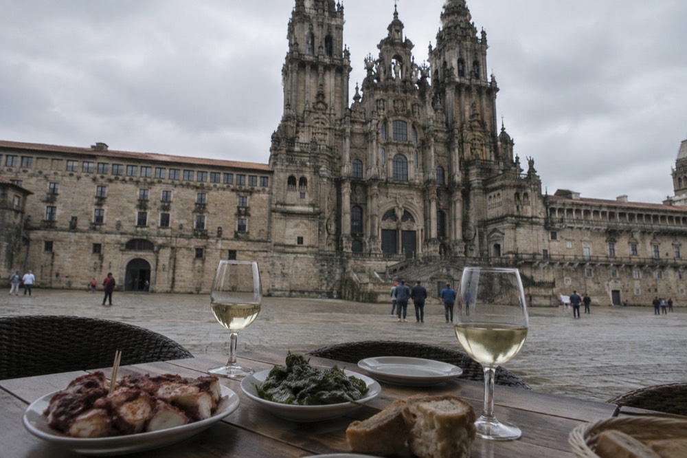 A Galician table with plates of octopus, fried peppers and glasses of white wine