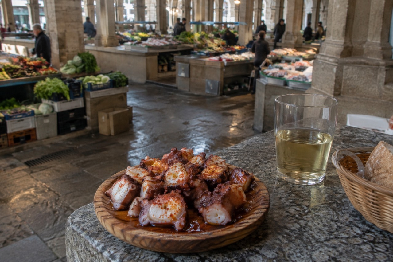 A wooden plate of boiled octopus with paprika and coarse salt on a stone tavern table