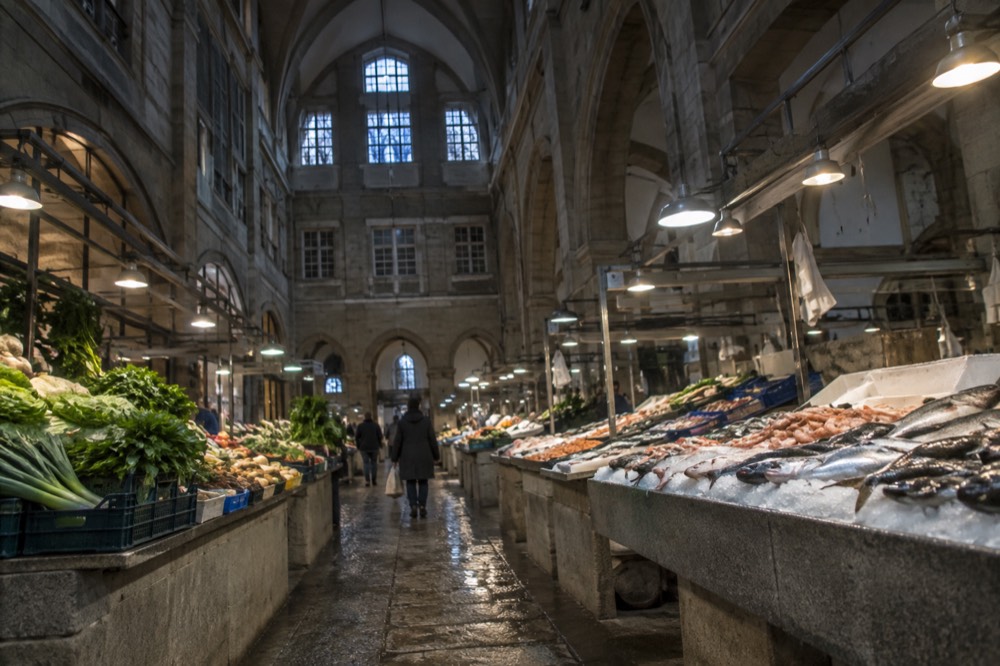 A covered market hall with stalls of fresh vegetables and fish