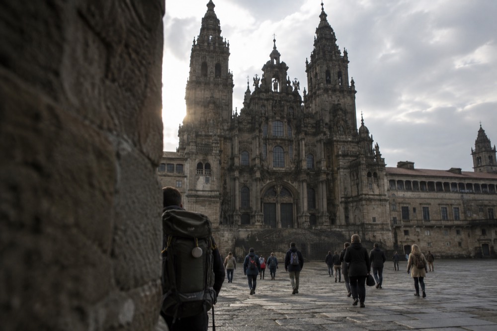 Pilgrims arriving at a stone marker on the Camino de Santiago route in rural Galicia