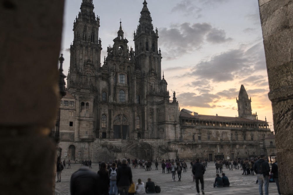 Crowds gathered on a stone square beside Santiago de Compostela Cathedral at dusk