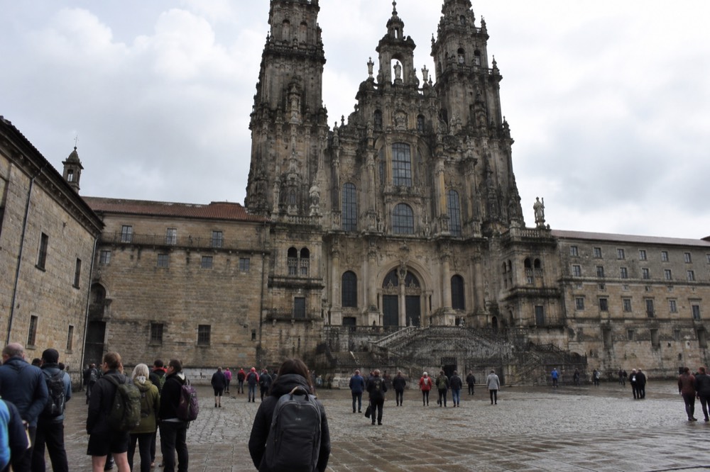 Pilgrims with packs waiting in line at a counter inside the Oficina del Peregrino in Santiago de Compostela