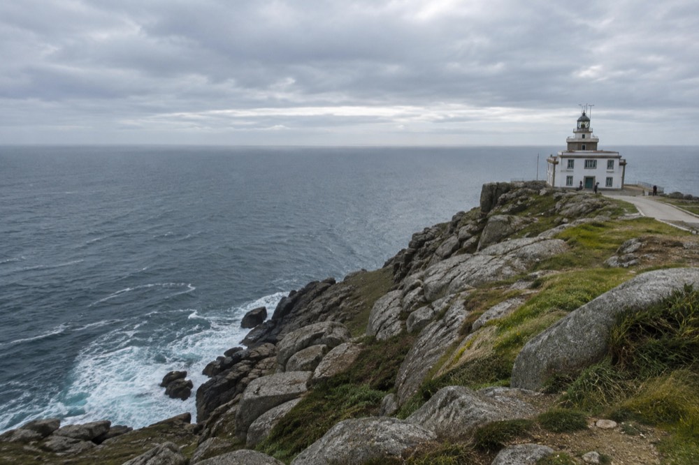 Rocky cliffs at Cape Finisterre with the ocean horizon stretching west under an overcast sky