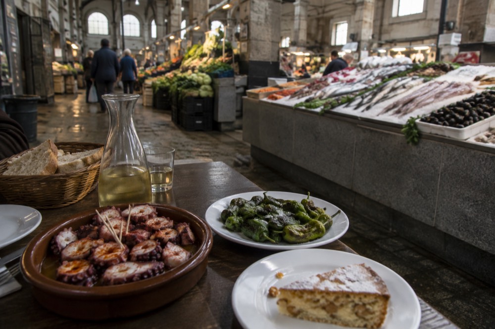 A spread of Galician tapas including octopus, peppers and almond cake on a tavern table