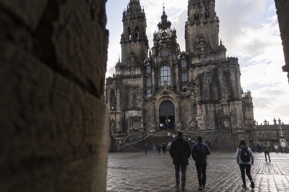 Visitors passing through a stone portal into the dim interior of the cathedral nave